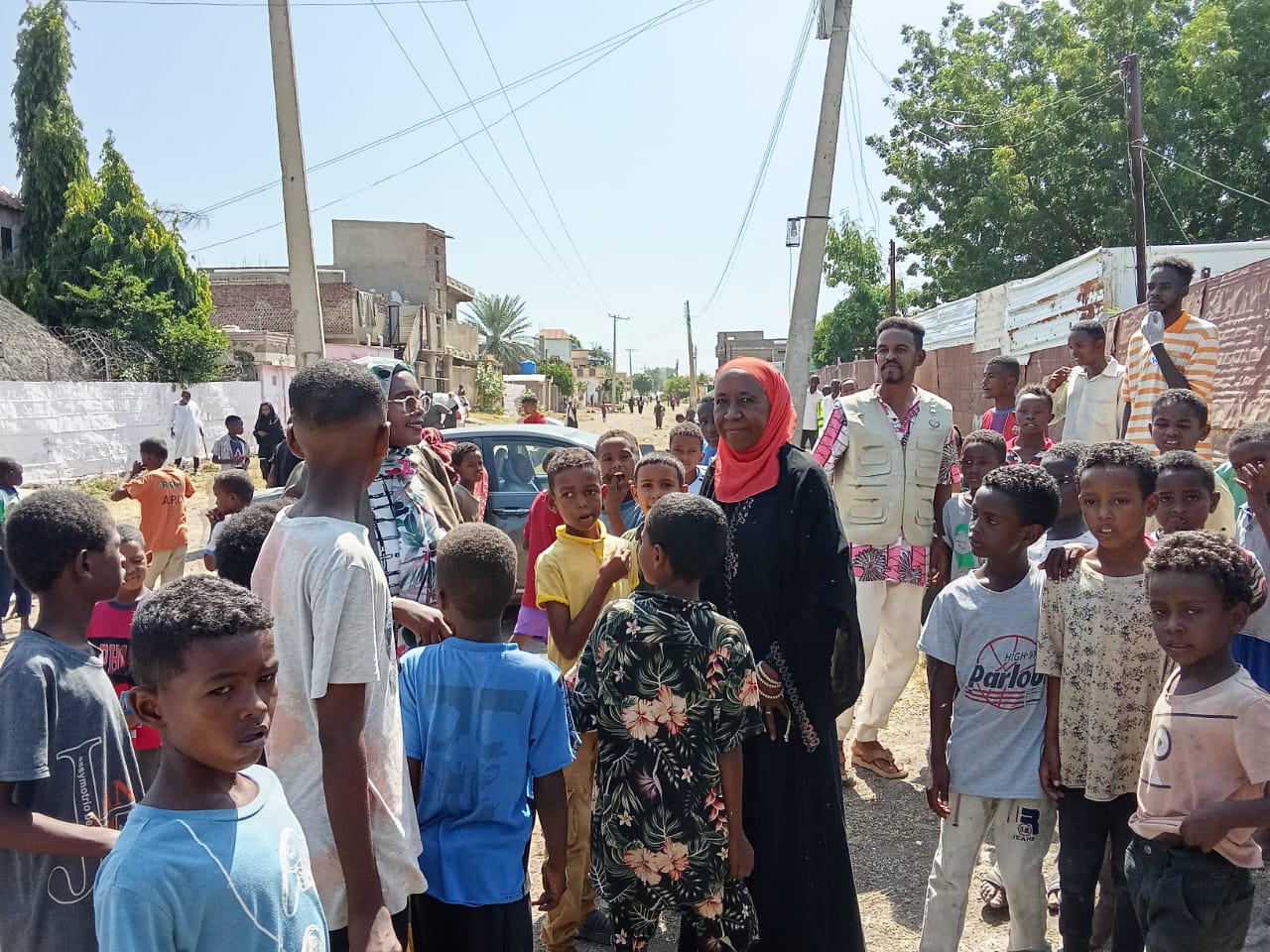 مجموعة من الأطفال مع أفراد من الفريق في الشارع